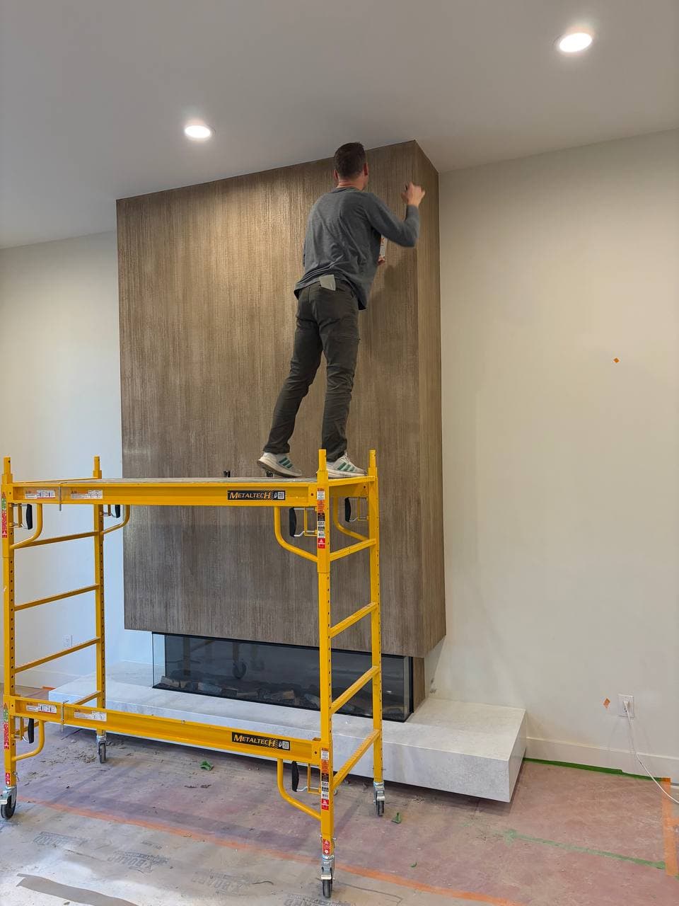Artisan applying the Thousand Lines texture to the fireplace, Barberton WA
